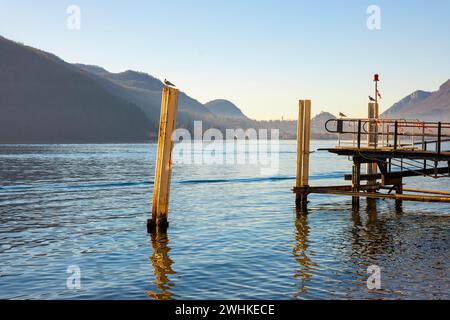 Jetée sur le lac de Lugano avec montagne et ville dans un jour ensoleillé avec ciel clair à Porto Ceresio, Lombardie, Italie Banque D'Images