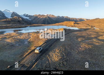 Vue aérienne, véhicule hors route sur piste de gravier, sommet de montagne et lac de montagne, ambiance nocturne, lac Arabel à Arabel Pass, province d'Issyk Kul Banque D'Images