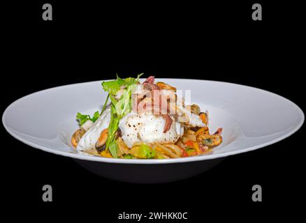 Filet de skrei norvégien rôti sur légumes colorés, avec anchois, moules, armoiries de poulpe, crevettes, coriandre fraîche et estragon, nourriture Banque D'Images