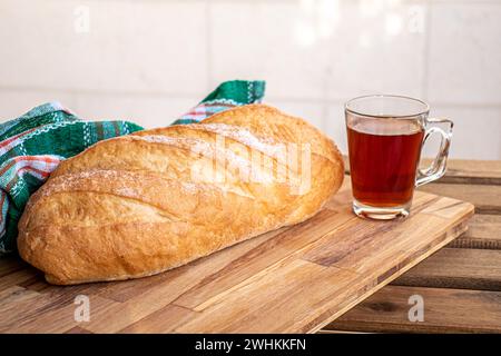 Pain sur table en bois prête à être servie et tasse de thé sur fond blanc Banque D'Images