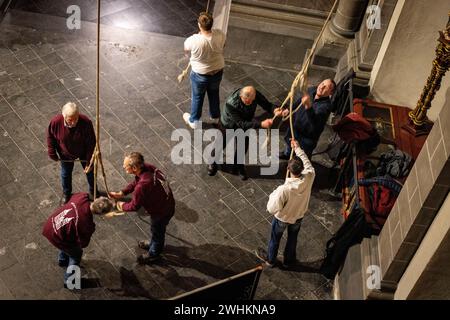 Xanten, Allemagne. 10 février 2024. Les membres de la compagnie de sonnerie tirent sur trois cordes samedi soir pour sonner les trois grosses cloches de la cathédrale. La « compagnie de sonnerie » de la cathédrale de Xanten sonne dimanche à la main 13 hommes, pour la plupart des retraités, sonnent à la main les trois grosses cloches de la cathédrale sur des cordes de 40 mètres de long. Ils suivent une chorégraphie fixe - parfois ils en pendent trois à une corde. Crédit : Christoph Reichwein/dpa/Alamy Live News Banque D'Images