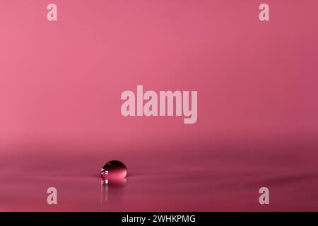 Chute de goutte d'eau tombe sur la surface de l'eau, fond coloré, photo de studio Banque D'Images