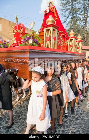 Antigua, Guatemala. Semana Santa (semaine Sainte). Jeunes filles portant une Anda (flotteur) de la Vierge Marie dans une procession religieuse. Banque D'Images