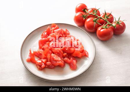 Tomates, entières et hachées sur une assiette, ingrédient pour divers plats, concept de cuisine saine, espace de copie, focus sélectionné Banque D'Images