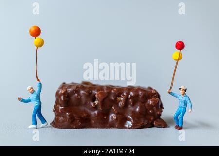 Enfants avec des barres de chocolat debout sur fond gris. Concept de la Journée mondiale du chocolat Banque D'Images