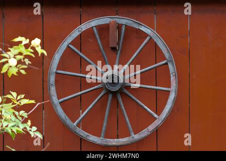 Roue d'une calèche suspendue à un mur de bois rouge. Tourné en Suède, Scandinavie Banque D'Images