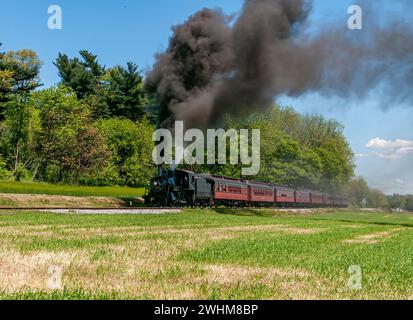 Vue d'un train de passagers à vapeur antique restauré, approchant, soufflant de la fumée noire Banque D'Images