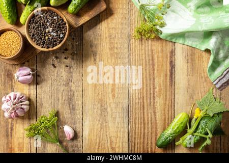 Fond en bois avec des concombres préparés pour le marinage et des ingrédients pour la marinade. Légumes en conserve. Maquette. Récolte pré Banque D'Images