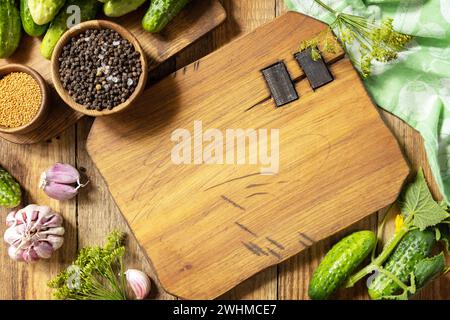 Fond en bois avec des concombres préparés pour le marinage et des ingrédients pour la marinade. Légumes en conserve. Maquette. Récolte pré Banque D'Images