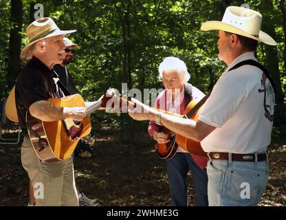 Les musiciens s'affrontent en groupes fluides sous les arbres au pique-nique Old Fiddlers Banque D'Images