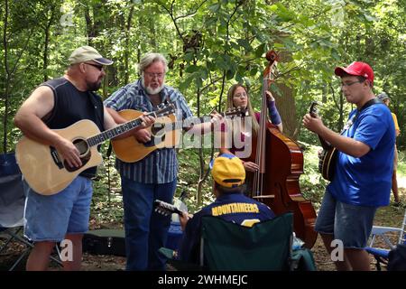 Les musiciens s'affrontent en groupes fluides sous les arbres au pique-nique Old Fiddlers Banque D'Images