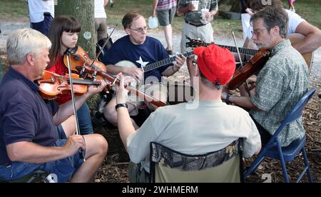 Les musiciens s'affrontent en groupes fluides sous les arbres au pique-nique Old Fiddlers Banque D'Images