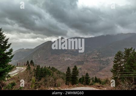 Nuages sombres au-dessus des montagnes Pindus et des sapins vus depuis le village traditionnel d'Elati, près de la ville de Trikala, dans la région de Thessalie, Grèce centrale, Banque D'Images