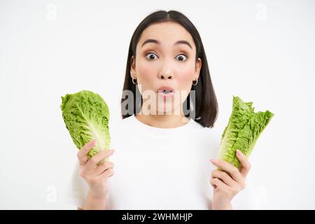 Alimentation saine et aliments biologiques. Femme asiatique souriante montrant du chou, mangeant de la laitue, nettoyant son corps, sur la désintoxication, backgrou blanc Banque D'Images