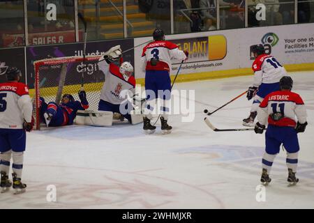 Cardiff, 10 février 2024. Ben Davies jouant pour la Grande-Bretagne est entaché et atterrit dans le filet lors d'un match de qualification olympique de hockey sur glace contre la Serbie au Vindico Arena, Cardiff. Crédit : Colin Edwards/Alamy Live News. Banque D'Images