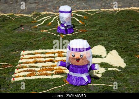 Antigua, Guatemala. Les poupées de Cucuruchos décorent une alfombra (tapis) d'aiguilles de pin et d'autres matériaux traditionnels dans une rue en avant des pas Banque D'Images