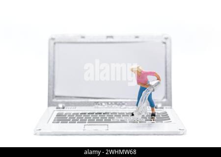 Les personnes miniatures nettoyant l'ordinateur portable sur fond blanc Banque D'Images