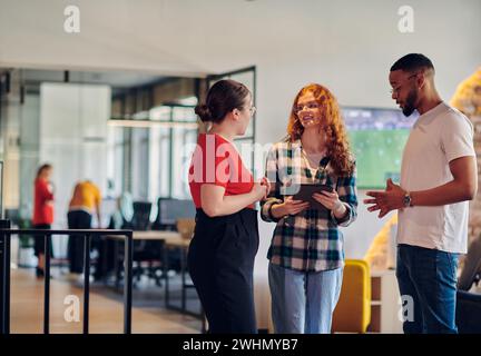 Un groupe de jeunes gens d'affaires, y compris une fille aux cheveux orange et un homme afro-américain, se tient dans un corpus moderne Banque D'Images