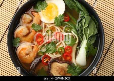 Délicieux ramen avec des crevettes et oeuf dans un bol sur tapis de bambou, vue de dessus. Soupe de nouilles Banque D'Images