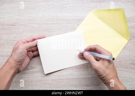 Les hommes écrivent des cartes vides sur une table en bois. Banque D'Images