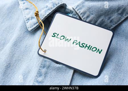 Consommation consciente. Étiquette avec mots Slow Fashion sur chemise en denim, gros plan Banque D'Images