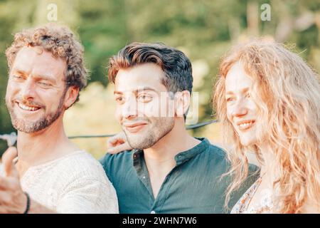 Petit groupe d'amis prenant une photo selfie souriant à la caméra, riant les jeunes célébrant debout dehors et ayant fu Banque D'Images