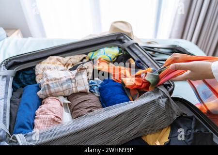 Femme emballant valise sur le lit pour une nouvelle liste d'emballage de voyage pour la planification de voyage préparer des vacances Réservez maintenant Voyage transport Banque D'Images