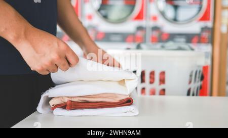 Homme faisant blanchir le panier tenant avec le linge sale de la machine à laver dans le magasin public. concept de vêtements de lessive Banque D'Images