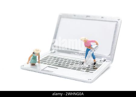 Les personnes miniatures nettoyant l'ordinateur portable sur fond blanc Banque D'Images
