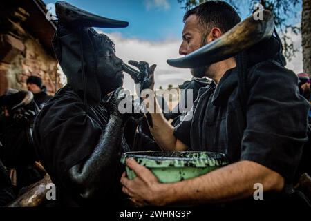 Madrid, Espagne. 10 février 2024. Un homme peint le visage d'un autre homme en noir pendant les festivités de Luzon. Une fois de plus, la ville de Luzon, près de Guadalajara en Castilla la Mancha, en Espagne, a célébré sa fête traditionnelle des diables de Luzon où certains habitants peignent leurs visages et s'habillent en noir et portent des cornes et des cloches tandis que d'autres couvrent leurs visages avec des masques blancs de genre. Le festival a plus de 50 ans. Crédit : SOPA images Limited/Alamy Live News Banque D'Images