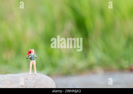 Mini figurine miniature Traveler avec support de sac à dos et marchant sur la prairie Banque D'Images