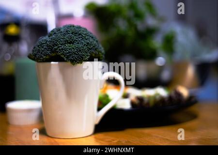 Brocoli frais dans une tasse en céramique sur fond flou. Banque D'Images