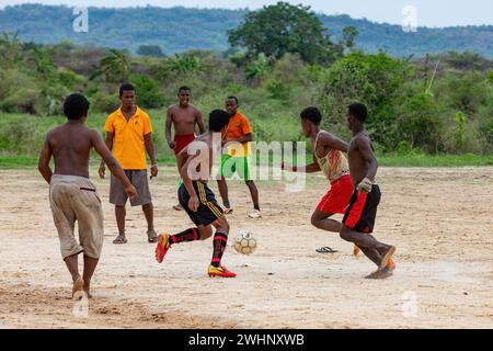 Un groupe de jeunes hommes jouent au football sur un terrain en terre battue à Bekopaka, Madagascar Banque D'Images