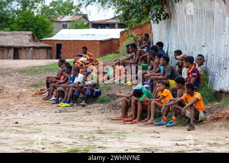 Fans de football assis sur le sol et regardant un match local entre deux équipes du village. Bekopaka Madagascar Banque D'Images