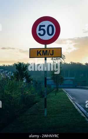 Route de campagne dans une zone résidentielle avec un panneau de limitation de vitesse à 50 km/h. Banque D'Images