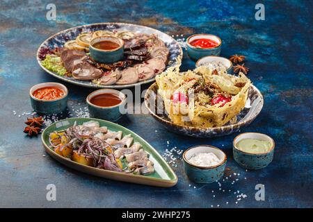 Plat avec divers apéritifs froids à la viande, salade de viande dans un panier de fromage et hareng salé avec pommes de terre et oignons Banque D'Images