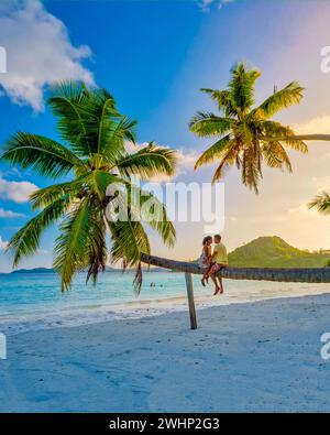 Praslin Seychelles île tropicale avec des plages de withe et des palmiers, couple hommes et femme en hamac balançoire sur la plage sous un Banque D'Images