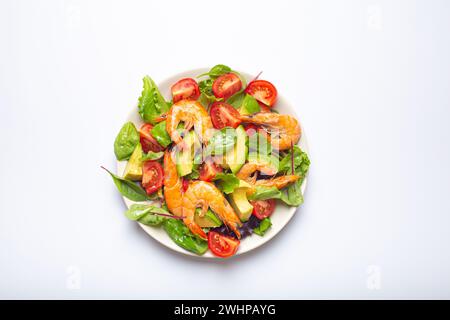 Salade saine avec crevettes grillées, avocat, tomates cerises et feuilles vertes sur plaque blanche isolé sur fond blanc top vi Banque D'Images