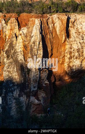 Homme grimpant mur de roche attaché par des cordes à son partenaire. Silhouette d'un grimpeur reflétée dans le rocher. Banque D'Images