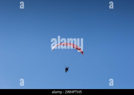 Homme vu parapente dans un ciel clair dans la Sierra Norte de Sevilla, Espagne Banque D'Images