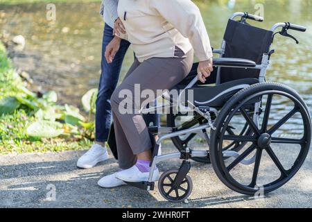 Maison de retraite. Jeune soignant aidant une femme âgée en fauteuil roulant. Banque D'Images