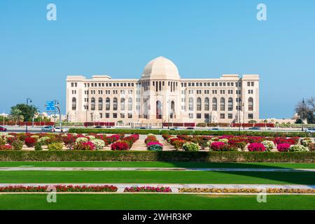 Vue de face à la Cour suprême d'Oman à Muscat, Oman. Jardins de jour ensoleillés au premier plan. Banque D'Images