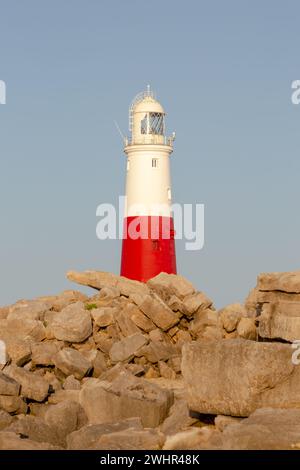 Phare de Portland Bill dans la lumière du coucher du soleil. Prise de vue verticale. Rochers devant. Banque D'Images