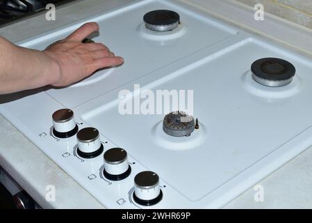 Sur l'image, la main d'une femme enlève les brûleurs avant de commencer à laver la surface de la cuisinière à gaz. Banque D'Images