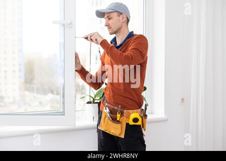 maître en gants de protection, changer une fenêtre à double vitrage dans une fenêtre en plastique. Banque D'Images