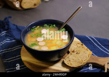 Soupe de pois jaunes avec saucisse mignonne dans un bol bleu avec des tranches de pain d'olive Banque D'Images