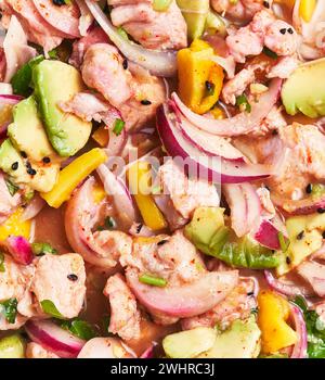 Gros plan d'un ceviche de fruits de mer vibrant avec saumon, avocat, mangue, oignon, coriandre, et du jus de citron vert, reflétant une cuisine fraîche Banque D'Images