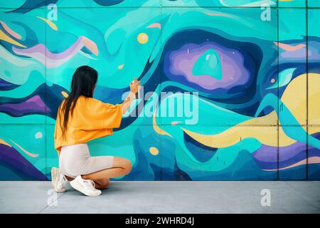 Artiste de rue peignant des graffitis colorés sur le mur Banque D'Images