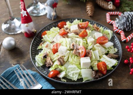 Salade de Noël d'hiver. Délicieuse salade avec chou chinois, feta, tomates cerises et thon en conserve sur une table de fête. Banque D'Images