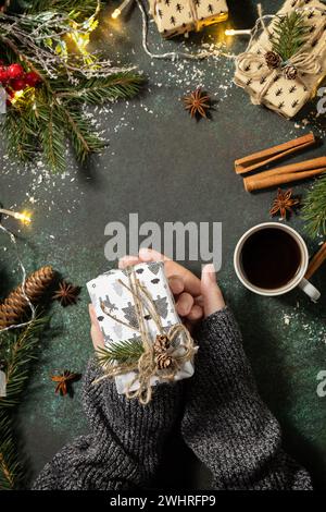 Concept hiver. Flatlay composition avec des mains féminines tiennent le cadeau de Noël et de café sur un fond de pierre sombre. Copier spac Banque D'Images